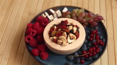 Taze meyve, fındık, mavi tabakta bir bardak meyve suyu, gösterişli çevre dostu, çiftlik kaynaklı ürünler. Vitaminlerle, besinlerle, antioksidanlarla dolu mükemmel temiz yiyecekler kırsal ahşap masaya güzelce yerleştirilmiş.