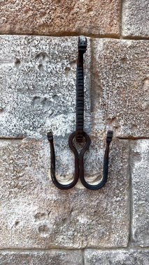 Kaba metal işçiliği ve taş sergilenen engebeli metal kanca, geleneksel zanaatkarlığı vurguluyor ve kırsal ortamlarda hammaddelerin dayanıklılığını sürdürüyor. 