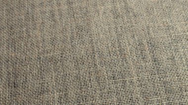 Dokulu çuval bezi, yakından bakınca pürüzlü lifleri ortaya çıkarır. Işık, el yapımı dokuma tasarımı, kırsal estetik ve doğal kusurları vurguluyor.. 