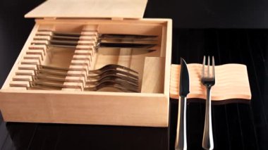 Gümüş bıçaklar ve çatallar ahşap kutuda düzgün dizilmiş, minimalist tasarımı vurguluyor. Modern yemek ayarları için eko-bilinçli depolama çözümü, sürdürülebilir materyalleri stille birleştirmek 