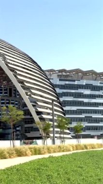 Şehir manzarasında metalik cephe ve yeşillik içeren modern mimari.