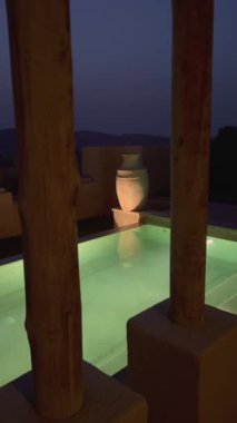 Gece vakti çöl otelinde ışıldayan yüzme havuzuyla parlayan turkuaz su dekoratif vazosu derin ışıklarla aydınlatılmış büyüleyici bir atmosfer yaratır ve büyülü, huzurlu bir vaha yaratır..