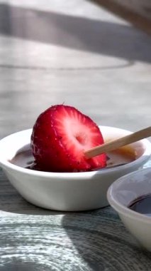 Lezzetli sosa batırılmış çilekler. Sos yavaşça damlıyor. Karşı konulamaz, hoşgörülü bir an yaratıyor. Tatlı cazibe ve yemek zevkini vurgulamak için mükemmel. Şehvetli, zarif.