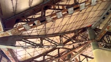 Paslı iskelet biçimleri terk edilmiş çöl yapısında karmaşık şebeke kalıpları oluşturuyor. Sütunlar yıpranmış panelleri tutuyor, endüstriyel bozulmayı ve yıllarca maruz kaldıktan sonra ıssızlığı ortaya çıkarıyor..