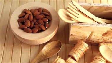 Ağaç çatal bıçak setiyle birlikte badem dolu ahşap kâse, çevre dostu ve doğal yemek seçeneklerini vurguluyor. Minimalist sunum sürdürülebilir yaşam tarzı ve doğal materyalleri vurguluyor.