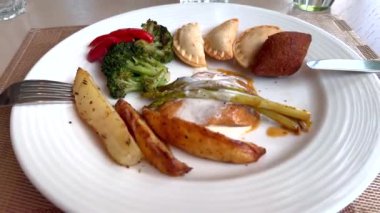 Baharatlı patates ve brokoliyle doldurulmuş Samosa, beyaz tabakta servis ediliyor. Klasik yemeklerin sağlıklı olması, canlı tatlar ve besleyici malzemelerin bir araya getirilmesi. Klasik 