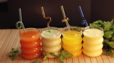 İçecekler yeşil, sarı, kaymak gibi gözlüklerle ahşap yüzeye saman konur. Sahne taze, sağlıklı içecekleri teşvik eder, doğal tatlarla rahatlığı ve suyu arttırır. Naneli. 