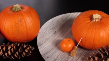 Pumpkins, orange, pinecones, broom evoke cozy Halloween festive vibe indoors. Vibrant autumn colors create warm seasonal atmosphere, highlighting rustic charm, perfect for festive gatherings. 