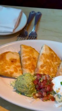 Taze avokado ve keskin domates salatası mükemmel tamamlayıcı gurme quesadilla, hepsi de birinci sınıf, çevre dostu malzemelerle yapılmış, sıcacık ve davetkar bir kafede sağlıklı bir yemeğin tadını çıkarın. 