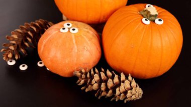 Pumpkins, googly eyes evoke playful Halloween feeling. Pinecones enhance rustic charm, creating cozy seasonal vibe, ideal for indoor gatherings, autumn decor, festive harvest setup.  clipart