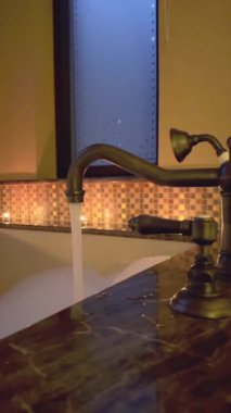 Romantik otel banyosu, mumlardan gelen sıcak ışık, köpüklü musluk doldurma küveti. Sakin su ve hafif ışıklandırma rahatlama ve hoşgörü için mükemmel bir ortam yaratır.