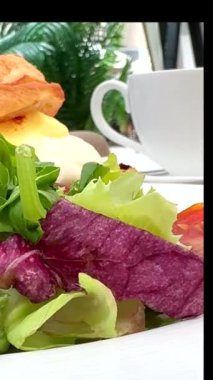 Yakınlarda farklı taze yeşillikli sandviç ve yanında da dumanı tüten bir fincan aromatik kahve. Tazeleyici sabah başlangıcı için mükemmel lezzet ve koku karışımı. Kahveci kahvaltı lezzeti.