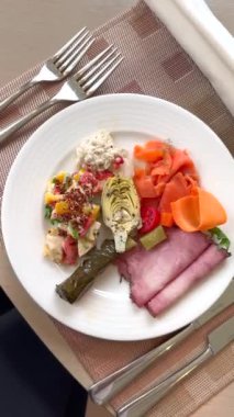 Soğuk kesimli tavuk salatası enginarları beyaz tabakta güzelce servis edilir. Bu lezzetli ve çevresel sorumlulukların bir karışımı olan rafine yemeğe bağlılığın somutluğudur.