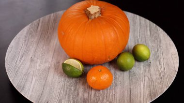 Pumpkin, limes, orange on rustic surface evoke seasonal Halloween spirit. Warm autumn colors and natural elements create cozy festive atmosphere, seasonal decor, harvest setting. clipart