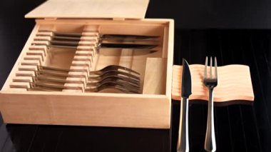 Gümüş bıçaklar ve çatallar ahşap kutuda düzgün dizilmiş, minimalist tasarımı vurguluyor. Modern yemek ayarları için eko-bilinçli depolama çözümü, sürdürülebilir materyalleri stille birleştirmek 