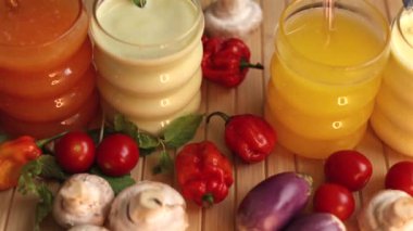 Köy yüzeyinde pipetli meyve suyu bardakları sebzelerin yanına dizilmiştir. Canlı renkler tazeliği vurgular, sağlıklı içecek ve yiyecek eşleşmelerini teşvik eder.