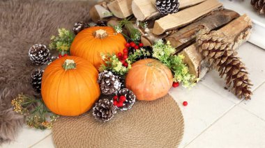 Thanksgiving decor features pinecones, red berries brighten cozy scene, pumpkins rest near soft white rug, firewood stacked nearby enhances autumn charm, cozy warmth emerges, festive glow concept. clipart