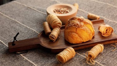 Croissant resting on wooden board surrounded by pastry rolls creates warm, cozy scene. Freshly baked pastry evokes comfort, rustic simplicity, inviting homemade breakfast feel.  clipart