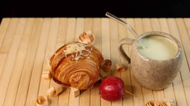 Ceramic mug filled with creamy vegetable beverage near croissant, autumn harvest setup emphasizing fresh produce, natural light, vibrant seasonal colors, rustic theme. clipart