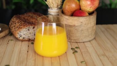 Bir bardak portakal suyu, tohumlu ekmek dilimi, ahşap armut kasesi ve ahşap yüzeyde buğday tohumu, sade, sade bir ortam, doğal ve sağlıklı yaşam tarzları için mükemmel..