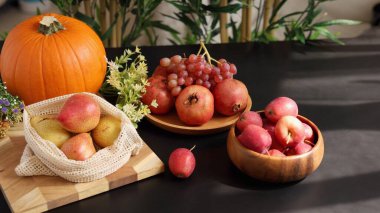  Balkabağı, armut, nar, üzüm ve elmalar, yeşillik ile koyu masa üzerinde düzenlenmiş canlı bir sonbahar sahnesi yaratarak, eko meyveleri ve mevsimlik eko hasat kavramını vurguluyorlar..