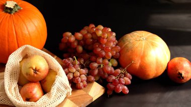 Eco harvest with orange pumpkin, red grapes, yellow pears, and pomegranate emphasizes natural fruits and berries. Eco-friendly produce promotes sustainable lifestyle for healthy living. 60 Keywords: clipart