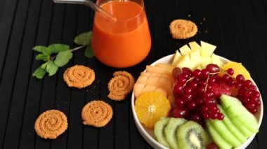  Ananas, kivi, kırmızı frenk üzümü, taze meyve suyu, siyah yüzeyde parlak turuncu ve yeşil renkler, canlı yaz havası yaratır. Sağlık sembolü, taze meyve suyu uyum kavramı.