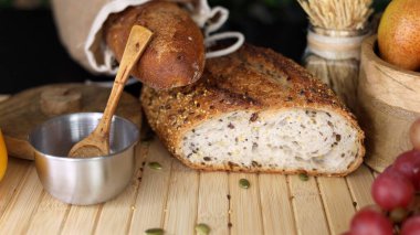 Çuval bezi çuvalı içinde tam tahıllı ekmek, bir kase tuz, tahta kaşıkla ahşap yüzey sıcak, davetkar bir sahne yaratır, çiftlikten sofraya promosyonlar için mükemmel, sağlıklı, doğal görseller..