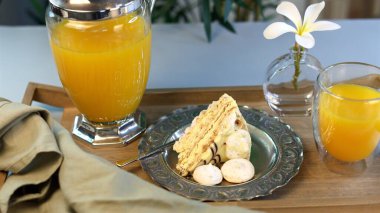 Sweet breakfast with golden cake slice, silver plate showing detailed patterns, beige meringues, vibrant orange juice in glass, blending nostalgic aesthetics with culinary elegance. clipart