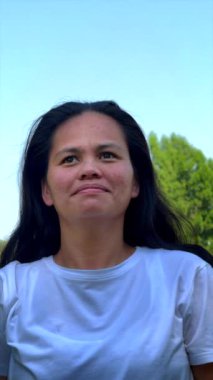 Güçlü, odaklanmış kadın doğa tarafından çevrili, dengeli yoga pozu veriyor, esnekliği, fiziksel gücü artırmayı hedefliyor, beyaz giysi ise yeşil çevreyi tamamlarken, sağlığını yansıtıyor.