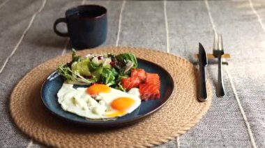 Taze yumurta, somon, yeşil salata ve nar tohumları mavi tabağa dizilmiş, koyu kahve, çevre bilinci açık, temiz yemek ve sağlıklı bir kahvaltı seçimi..