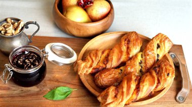  Organic-inspired breakfast display showcasing golden pastries, fresh fruits, nuts, jar of homemade jam, set in rustic and wholesome arrangement to emphasize health and simplicity. clipart