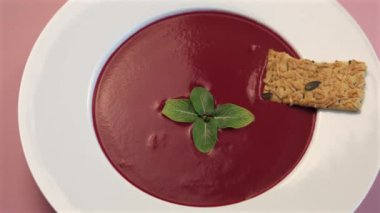 Minimalist pancar çorbası, naneli süsleme, koyu kırmızı tonlarda siyaha karşı çarpıcı görsel etki, temiz tasarım ve sadelik ve zarafete vurgu yaratır..