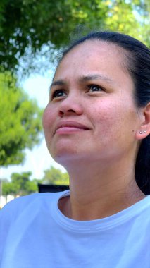 Odaklanmış kadın dışarıda yavaş nefes alıyor, çevresini çevreleyen canlı yeşillikler, besleyici rahatlama, iç sakinlik, sağIık, stres atağı için somut farkındalık, genel sağlık.