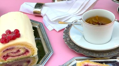 Pasta rulosu fincanın yanında, kremalı pasta kıvrımları dutlarla kaplı, dekoratif tepsi yükseltici antika masa dekorasyonu. Kupa zarif pasta stilini tamamlıyor. Tatlı cazibesi konsepti.