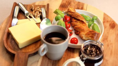 Cozy breakfast scene featuring twist bread, vibrant tomatoes, fresh basil paired with black coffee and cheese on wooden board, highlighting warm flavors and natural tones. clipart