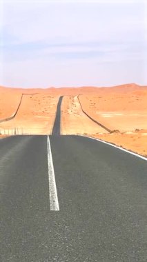 Çöl yolu, açık gökyüzü tarafından kucaklanan altın yabana doğru uzanır. Çölün çevresindeki kumlar macerayı, doğal uyumu ve el değmemiş engin güzellikle bağlantıyı simgeliyor..