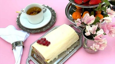 Pasta rulosu ile eşleştirilmiş kremalı pasta girdapları, parlak meyveler parlatılmış gümüş tepside. Ahşap arka plan, rustik pasta cazibesini ön plana çıkarıyor. Kupa piknik tatlısına odaklanıyor.. 