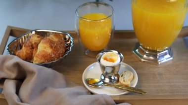 Sağlıklı kahvaltı seti; gümüş yumurta tutacağı, altın kaşık, taze pişmiş kruvasanlar ve canlı portakal suyu içerir. Rafine sabah sunumunda sanatsal güzellik sergilenir..