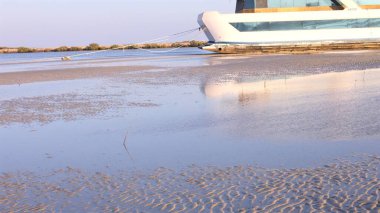 Stranded vessel resting quietly on soft sandy terrain amid tranquil reflections captures a poignant tale of halted journeys, embodying nature peaceful yet solemn beauty. clipart