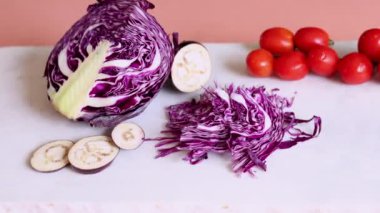 Mor lahana, dilimlenmiş patlıcan, doğranmış lahana ve kırmızı domatesler canlı organik gösteriler oluşturur. Eko renkleri, eko sunumu için doğal konsept ve organik üretimi vurguluyor.