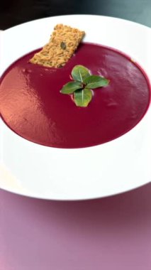 Pembe arka planla çarpıcı bir şekilde servis edilen pancar çorbası, taze nane ile süslenmiş, canlı minimalizmi vurguluyor, temiz tasarım, kalın görseller, estetik sadelik.