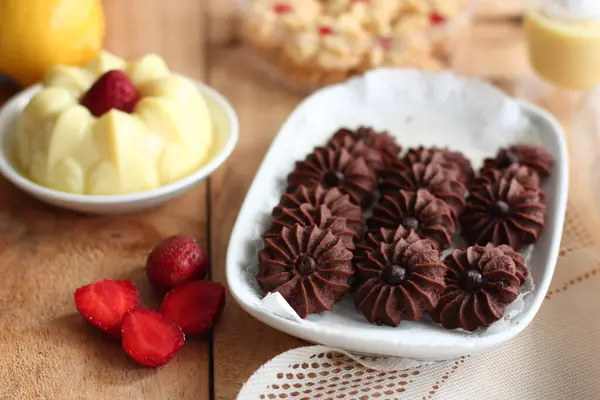 Çikolatalı kurabiye ve limonlu çilekli puding ile ahşap yüzeyde vanilyalı kurabiye.