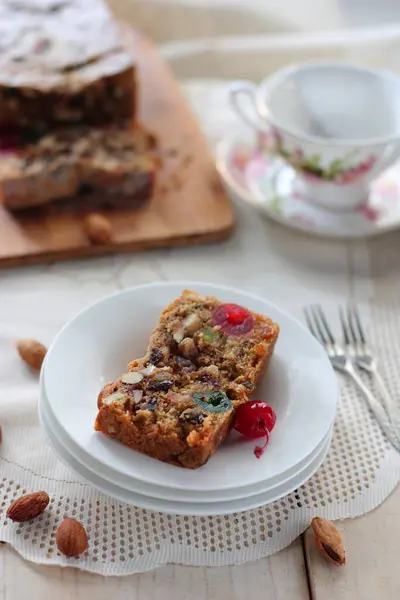 İngiliz meyveli keki, bir somun ekmek ve bir dilim porselen tabak ve bir fincan çay.     