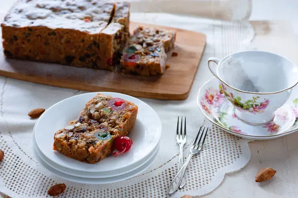 İngiliz meyveli keki, bir somun ekmek ve bir dilim porselen tabak ve bir fincan çay.     