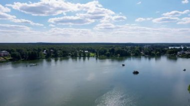 Hava aracı görüntüleri, sakin Peetzsee Gölü 'nü ve Gruenheide, Brandenburg' daki manzarayı, yoğun orman ve doğal güzelliklerle çevrili temiz bir gökyüzünün altında yüzen bir tekne ile yakalıyor..