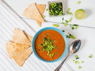 Taze domates çorbası fırınlanmış Pita ekmeği, limon ve taze soğan beyaz ahşap bir masada, üst manzara