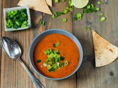 Taze domates çorbası fırınlanmış Pita ekmeği, limon ve taze soğan ahşap bir masada, üst manzara
