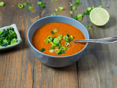 Taze domates çorbası fırında Pita ekmeği, limon ve taze soğan ahşap bir masada.