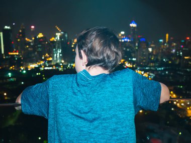 Bangkok, Tayland 'ın ufuk çizgisine bakan bir gencin arka görüntüsü.